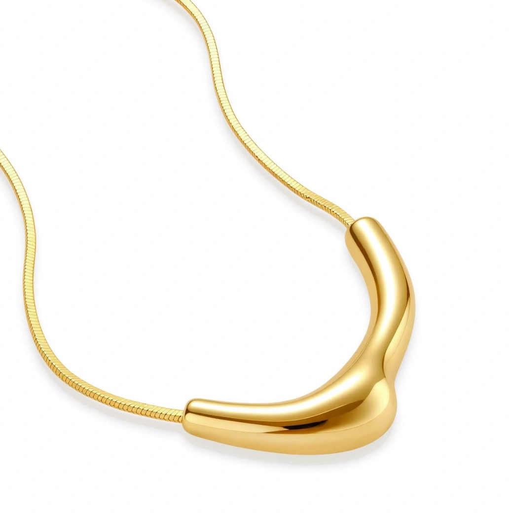 Minimalist gold-plated curved pendant necklace on delicate chain against cream background, showing adjustable length