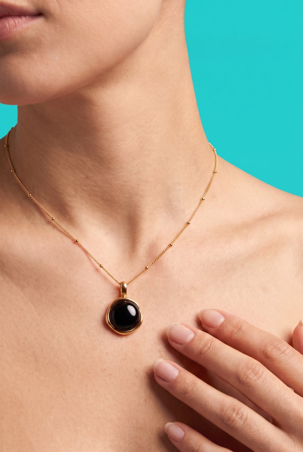 Minimalist gold-plated curved pendant necklace on delicate chain against cream background, showing adjustable length