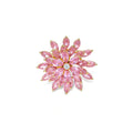 Pink cubic zirconia brooch in floral starburst design with palladium-plated copper setting on white background.