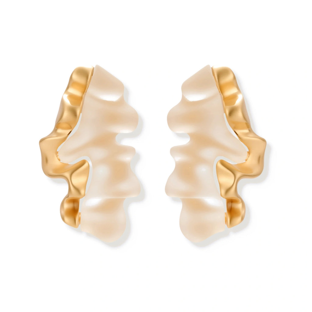 Sculptural wave-textured statement earrings with flowing organic ridges in metallic finish on cream background