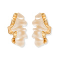 Sculptural wave-textured statement earrings with flowing organic ridges in metallic finish on cream background
