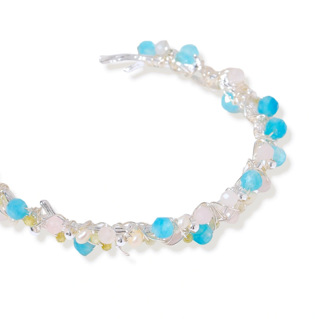 Delicate wire-wrapped bracelet featuring turquoise, rose quartz, freshwater pearls, and zircon on a white background.