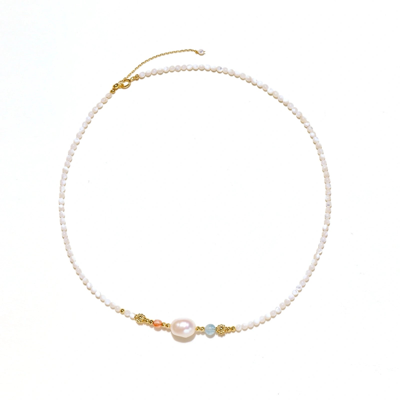 Delicate white beaded necklace with baroque pearl center, gold accents, and coral and aqua gemstones on cream background.