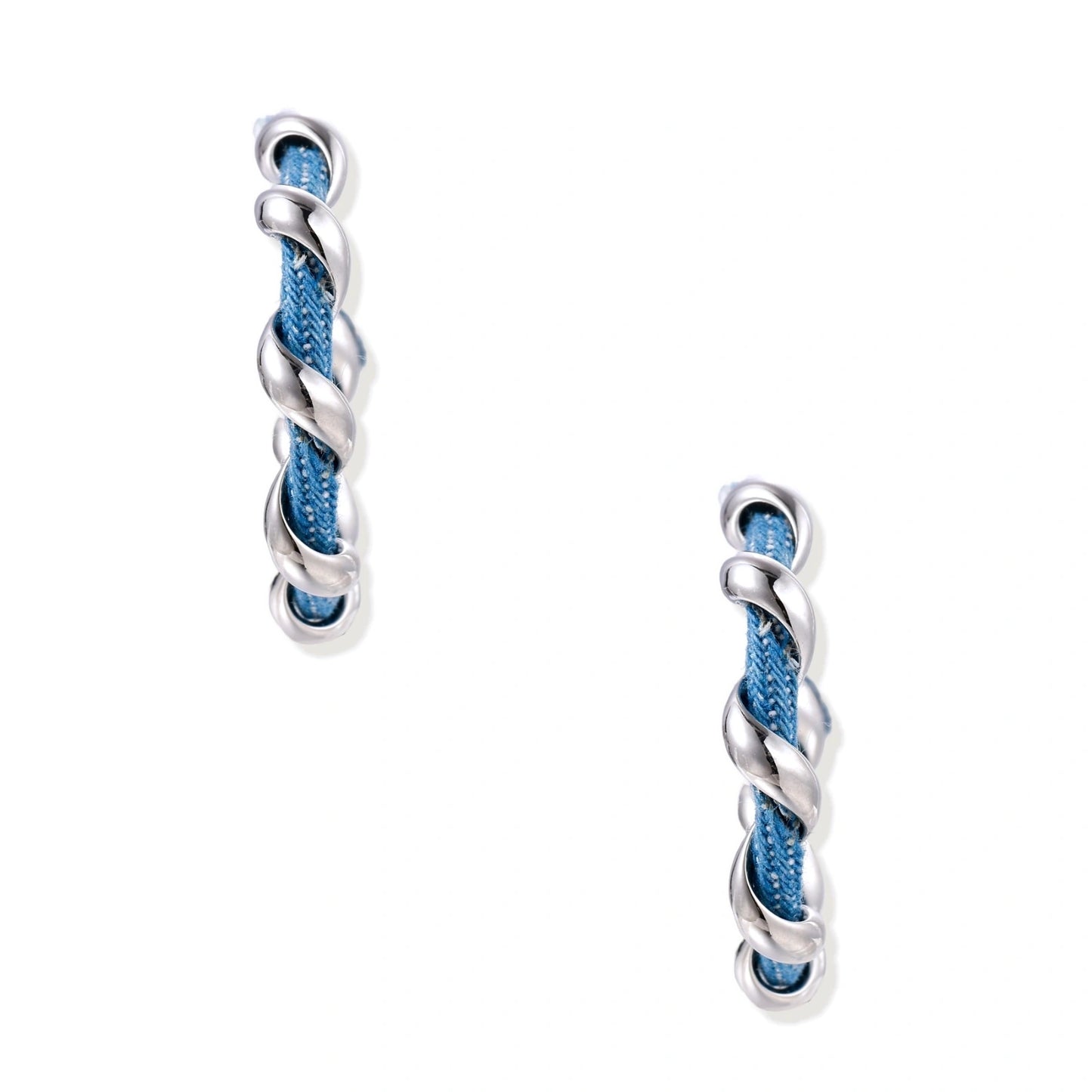White gold-plated hoops intertwined with blue denim fabric in a twisted rope design on cream background.