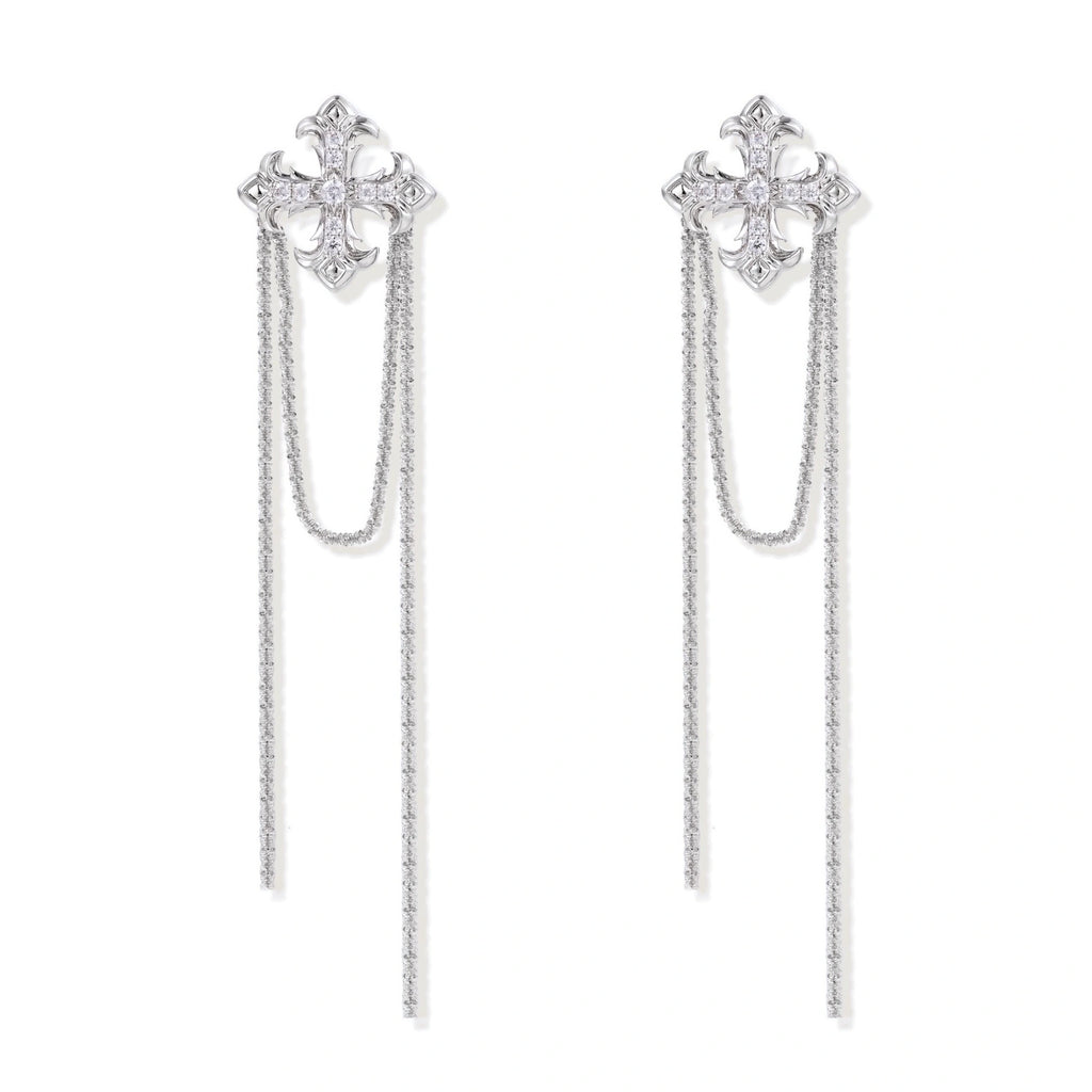 White gold plated baroque cross stud earrings with long cascading zirconia chains on cream background