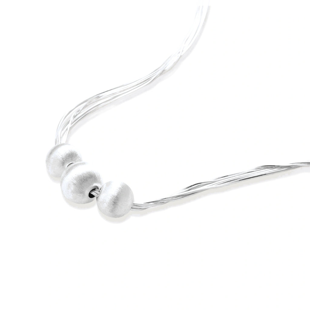 Sterling silver multi-strand necklace with three brushed round beads on cream background