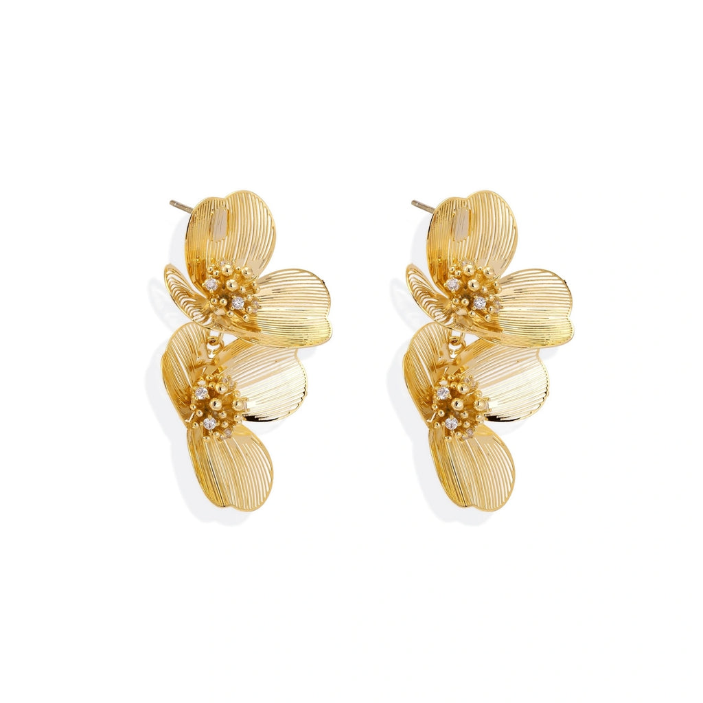 Pair of gold-plated double flower earrings with textured petals and crystal centers on cream background.