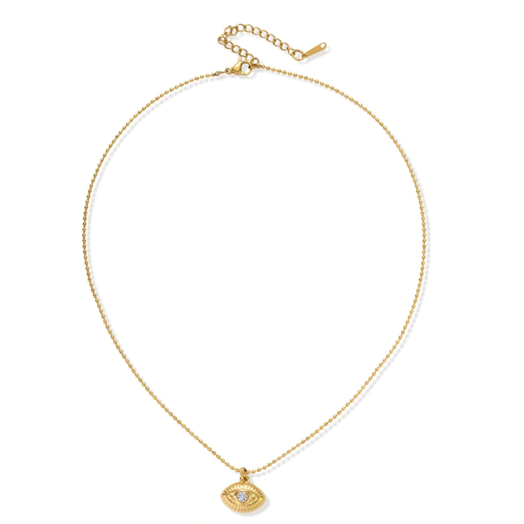 Layered necklace with green stone beads, gold spacers, white accents, and protective eye pendant on cream background.