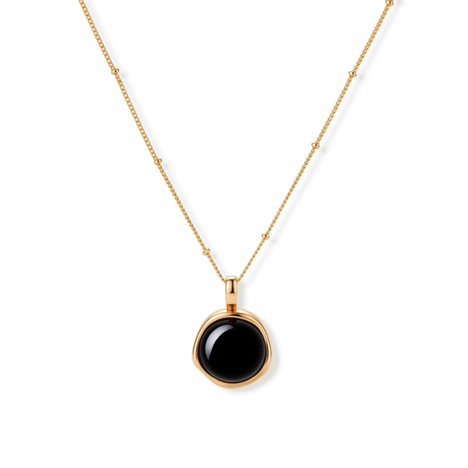 Circular black agate pendant on gold-plated sterling silver chain against cream background, showing modern minimalist design.