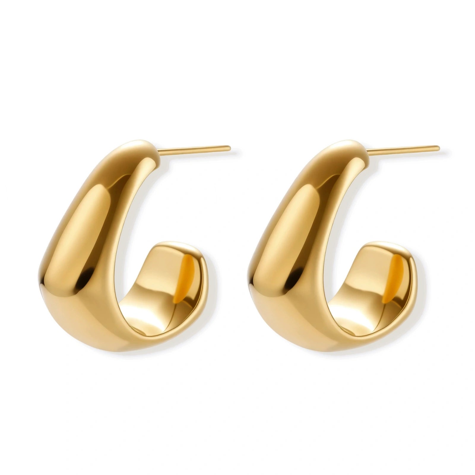 Close-up of curved gold-plated huggie earrings with sculptural design on white background, showing polished finish.