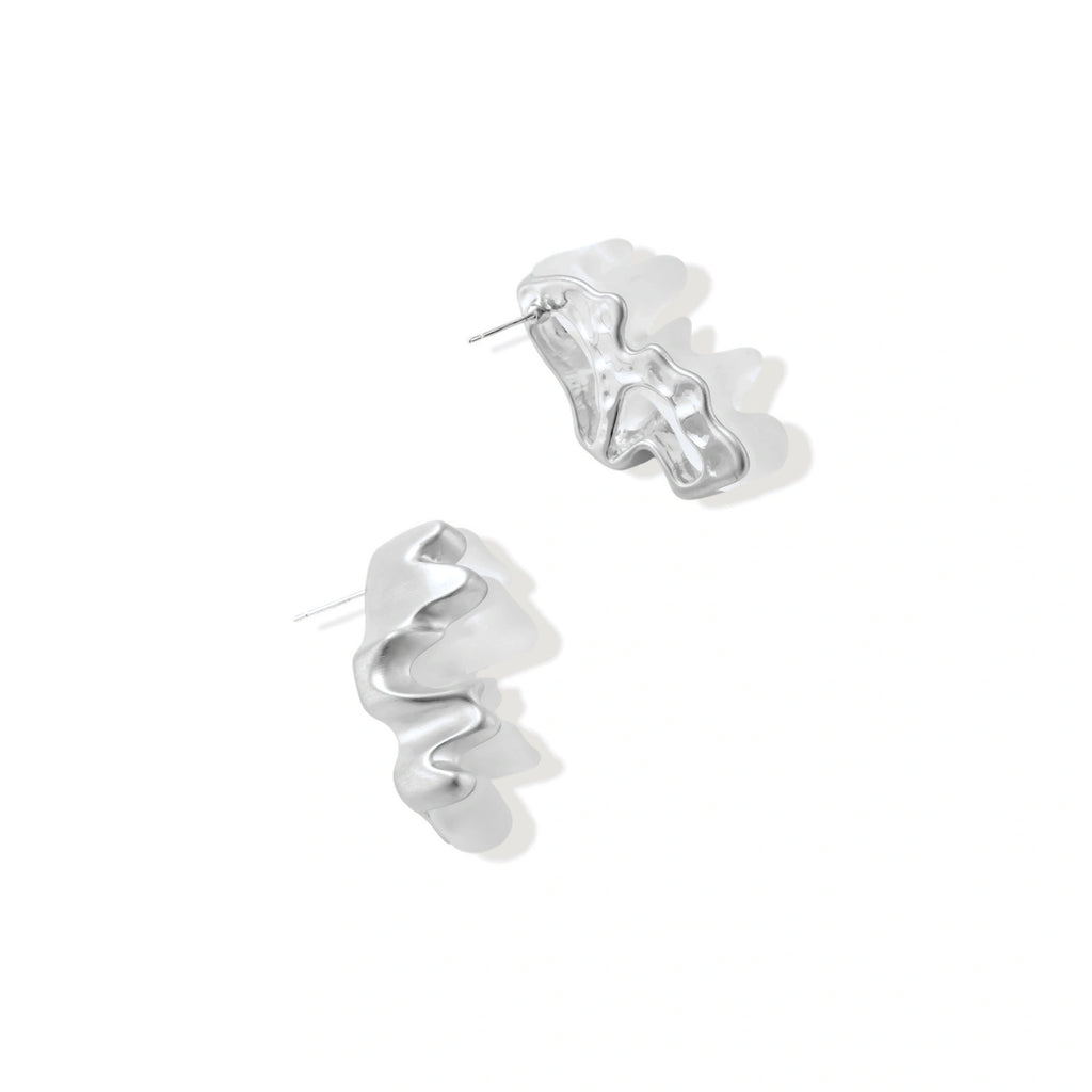Pair of silver-toned sculptural earrings with flowing abstract forms and stud backs against white background.