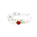 Three layered white beaded bracelets with carved orange agate lotus centerpiece and freshwater pearls on cream background.