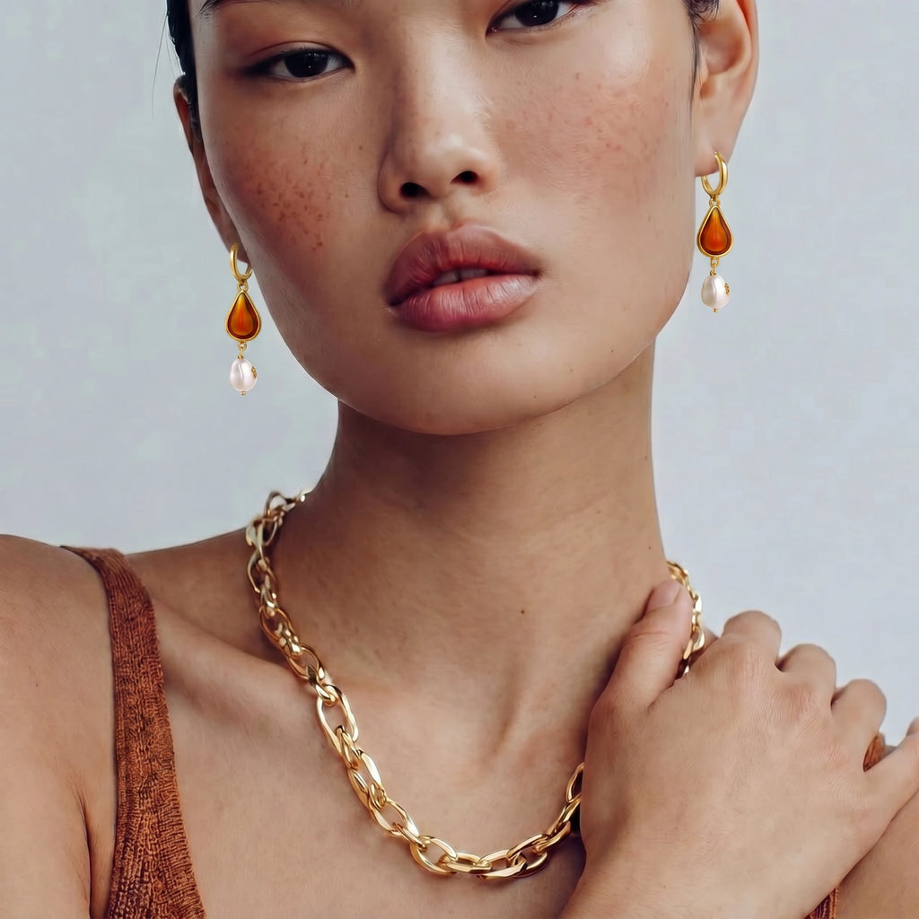 Woman wearing gold chain necklace and earrings with a plain background