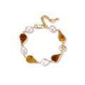 Elegant bracelet with alternating baroque pearls and amber teardrop gemstones set in 18k gold-plated copper on cream background.