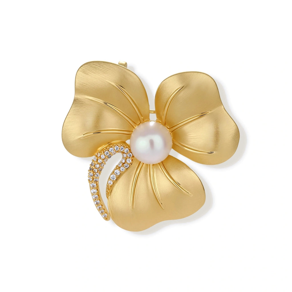 18K gold-plated copper flower brooch with five petals, white pearl center, and crystal stem accent on white background.