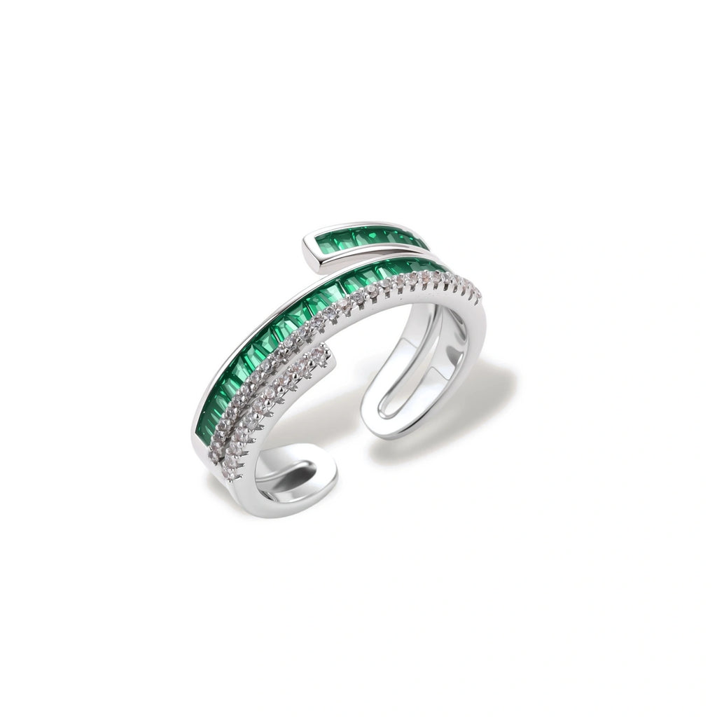 Modern adjustable ring with green baguette stones and clear crystals in parallel bands on white background.