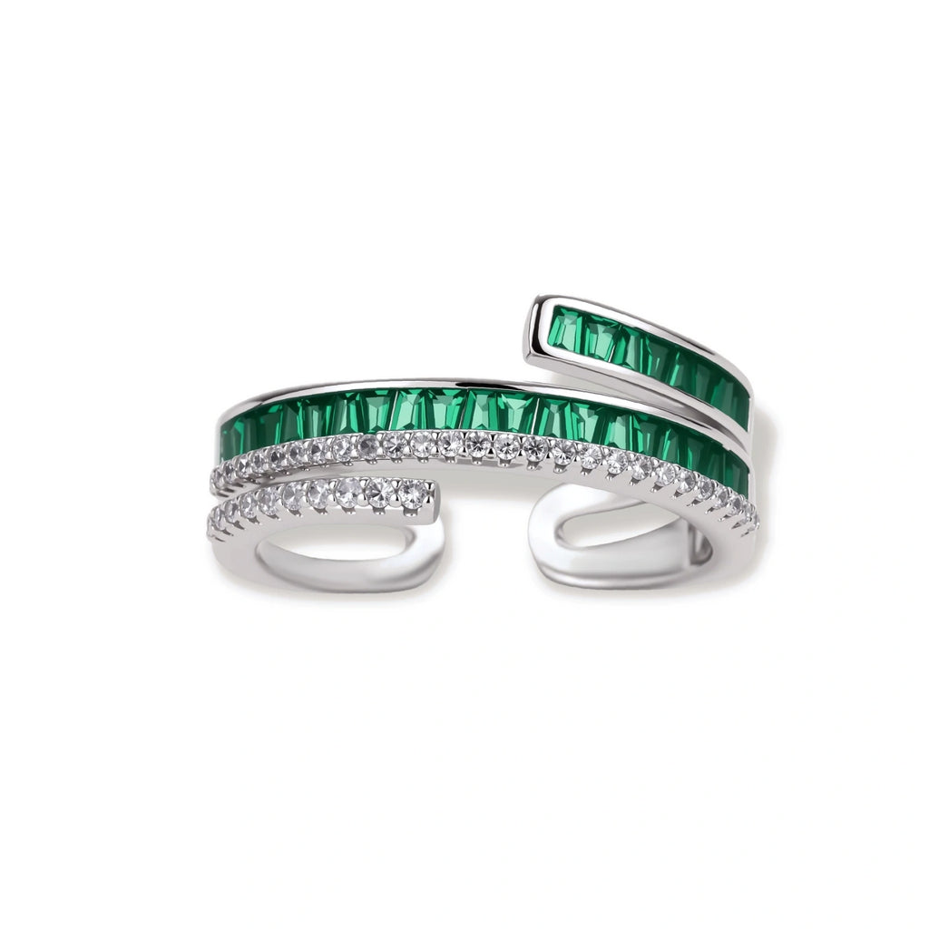 Modern adjustable ring with green baguette stones and clear crystals in parallel bands on white background.