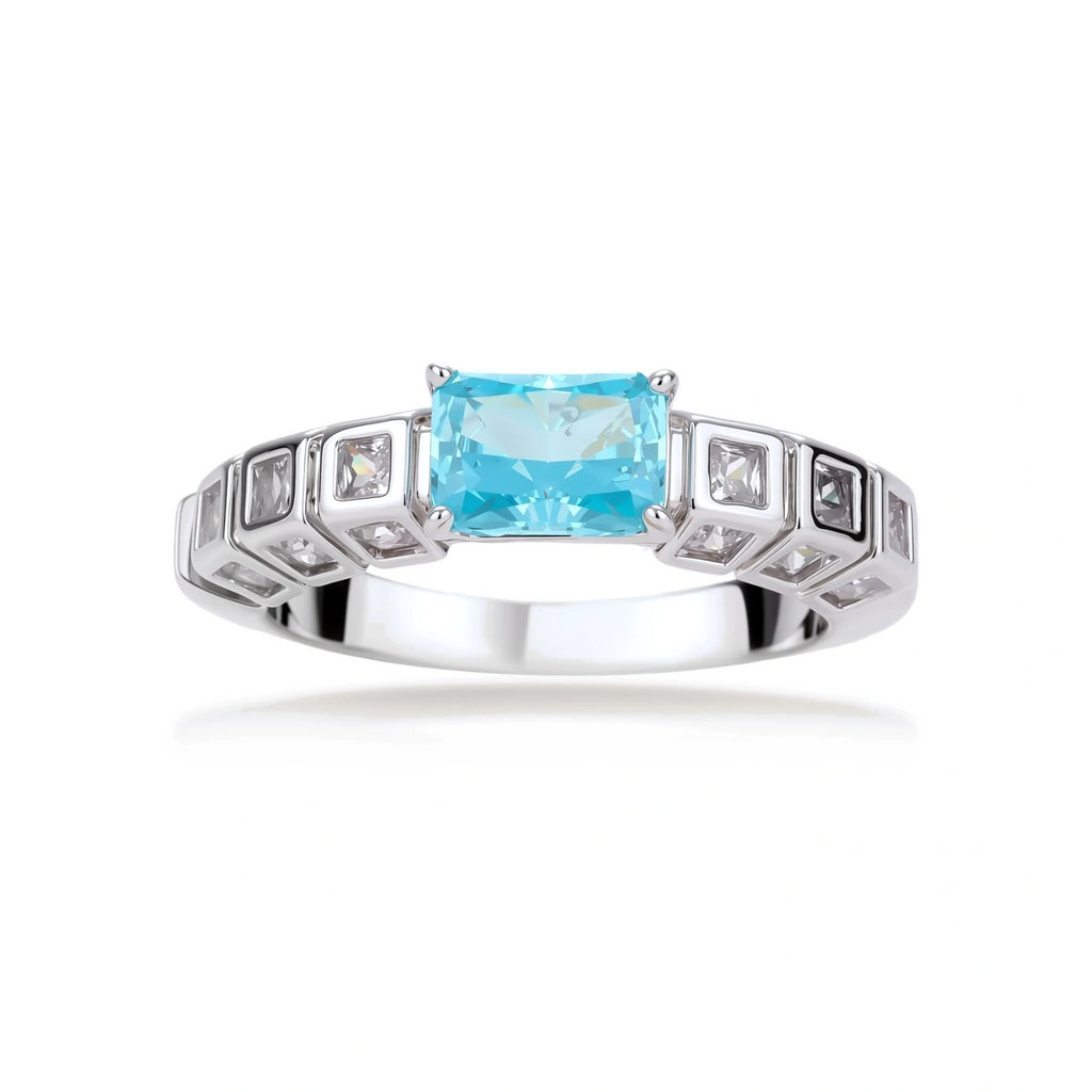 Geometric silver-plated ring with rectangular aqua cubic zirconia center and square crystal details on adjustable band.