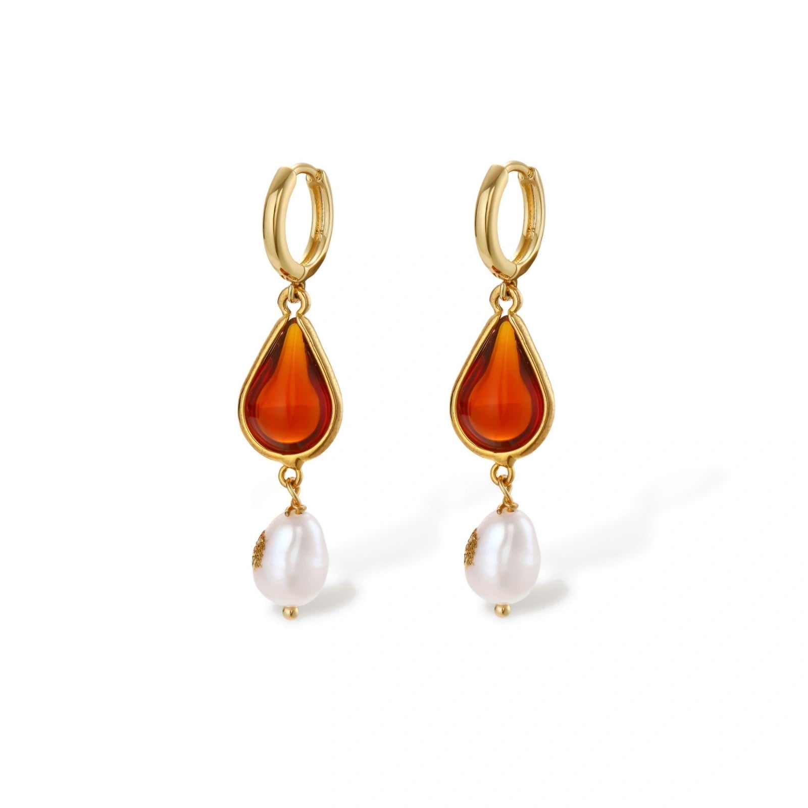 Gold-plated drop earrings featuring amber teardrops and white baroque pearls on light background.